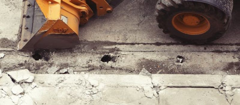 an excavator tearing up concrete